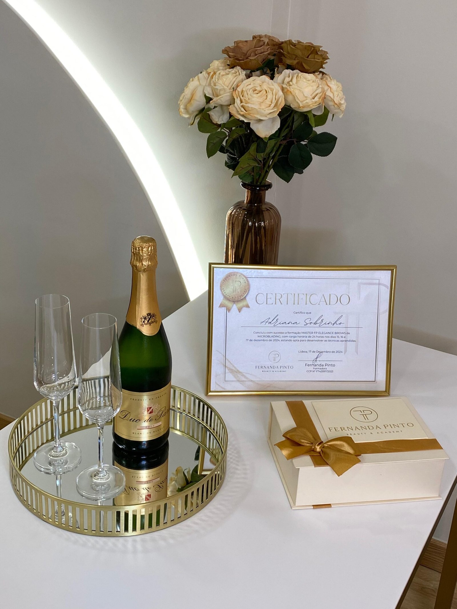 Kit do Curso de Microblading FP Elegance Brows com caixa dourada, certificado emoldurado, garrafa de espumante e dois flutes.
